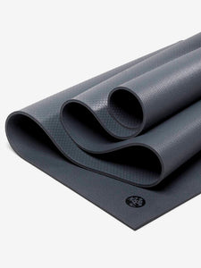 Close-up of a dark gray, non-slip, textured yoga mat partially rolled, side view showing thickness and surface detail, fitness accessory for yoga and exercise.