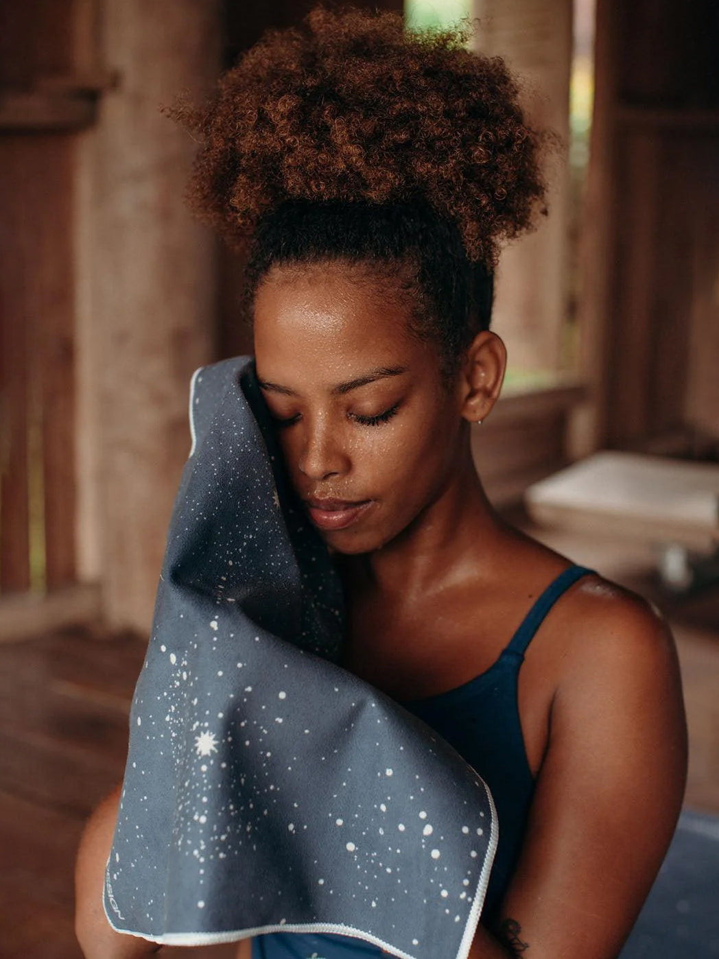 Woman holding a blue starry yoga mat, front view, eco-friendly material, non-slip texture, indoor setting, wellness and fitness accessory