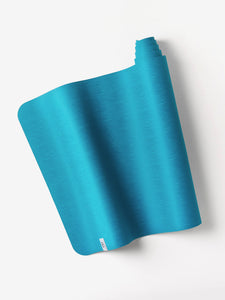 Blue textured yoga mat partially rolled on white background with visible brand tag