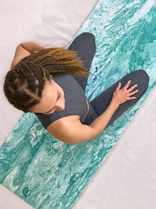 Woman practicing yoga on a teal marbled-pattern yoga mat, overhead shot, fitness and wellness concept